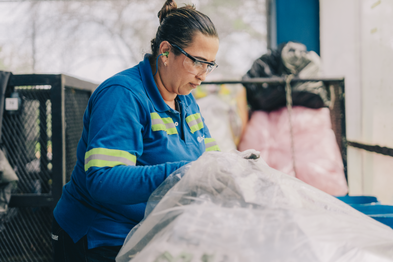 Operaria clasificando materiales aprovechables en una planta de reciclaje.