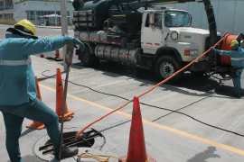 Operarios realizando mantenimiento de tuberías con equipo especializado y zona de trabajo señalizada.
